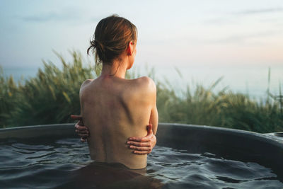 Side view of shirtless man standing in water