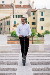 Portrait of man standing against building in city