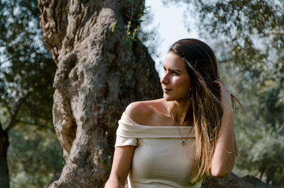 Young woman looking at tree trunk