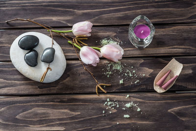 Close-up of pebbles with tea light candle and tulips on table