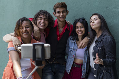 Portrait of smiling friends standing against wall