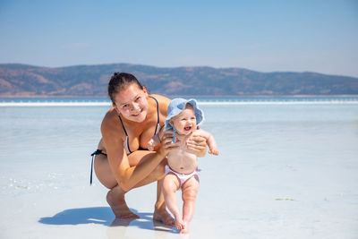 Portrait of happy friends on beach against sky