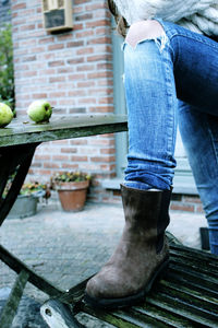 Low section of a girl stepping on a chair. boots and ripped jeans