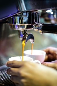 Close-up of hand pouring coffee in glass