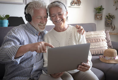 Senior couple using laptop while sitting on sofa at home