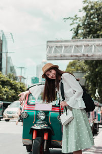 Portrait of woman standing against car in city