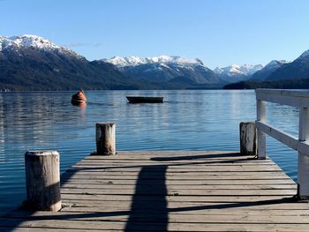 Pier over lake by snowcapped mountains against sky