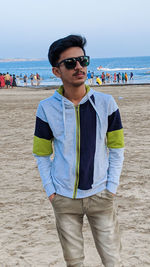 Portrait of young man wearing sunglasses standing on beach