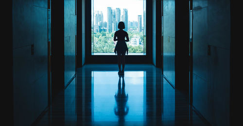 Silhouette of young woman standing on corridor