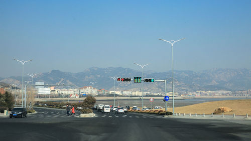 Vehicles on road against clear blue sky