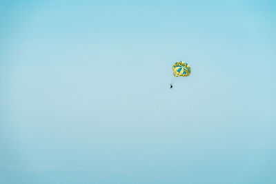 Low angle view of person paragliding against clear sky