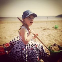 Woman holding sunglasses on beach against sky