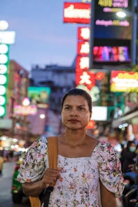 Portrait of smiling young woman standing in city