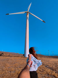 Low section of woman standing on field against clear blue sky