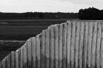 Close-up of wooden post on field against sky