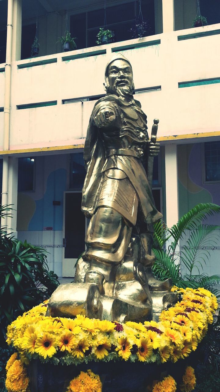 yellow, building exterior, architecture, flower, built structure, plant, window, statue, art, growth, day, building, human representation, outdoors, residential structure, house, art and craft, creativity, sculpture, city