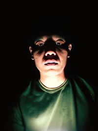 Portrait of young man against black background