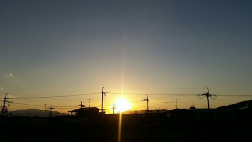 Low angle view of silhouette electricity pylon against sky during sunset