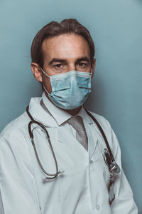 Portrait of doctor wearing mask against colored background