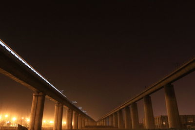 Low angle view of illuminated bridge against sky at night