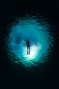 Silhouette boy swimming in sea