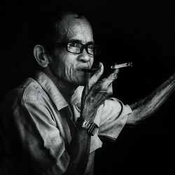 Portrait of man holding camera against black background