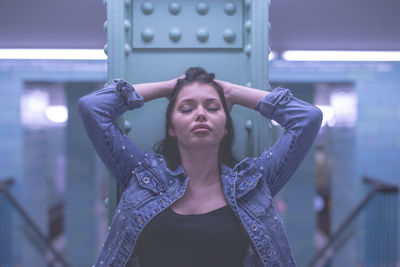 Young woman with hands in hair standing against column