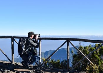 Man photographing against clear blue sky