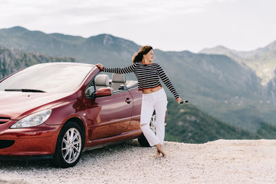 Woman standing on car against mountains