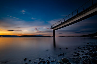 Bridge over sea against sky during sunset