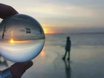 Reflection of crystal ball on water against sunset sky