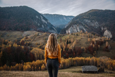 Rear view a of blonde female standing and enjoying the autumn mountains.travel and lifestyle concept