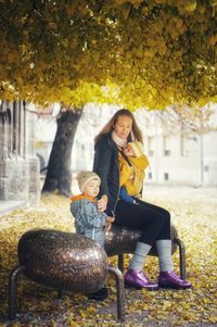 Portrait of young woman with toddler sitting at park