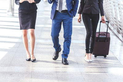 Low section of woman with luggage by man walking on elevated walkway