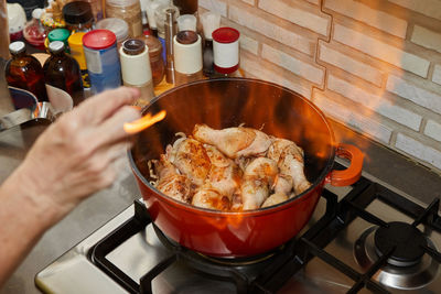 Flamber chicken legs in saucepan on the gas stove