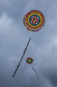 Low angle view of kites flying against sky