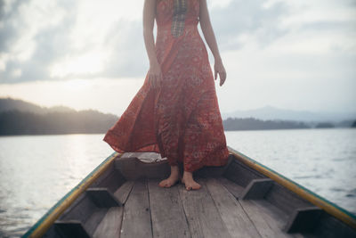 Low section of man standing on pier over calm lake