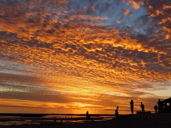 Silhouette beach against sky during sunset