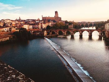 Bridge over river against buildings in city