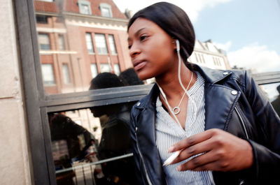 Close-up of young woman with window in city