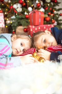 Portrait of cute girl on lying down by christmas tree