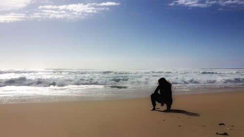 Rear view of woman on beach against sky