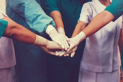 Midsection of surgeons stacking hands at hospital