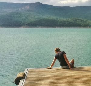 Rear view of woman sitting on lake