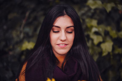 Close-up of young woman looking down while standing in forest during winter