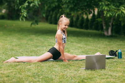 Girl with laptop exercising on field