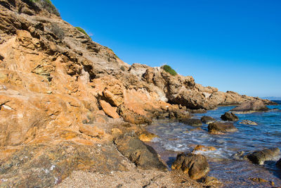 Rock formations in sea against clear blue sky