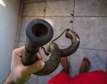 Close-up of hand holding metal against wall