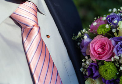 Midsection of man by flowers with ladybug on shirt