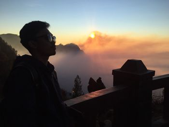 Side view of young man standing against sky during sunset